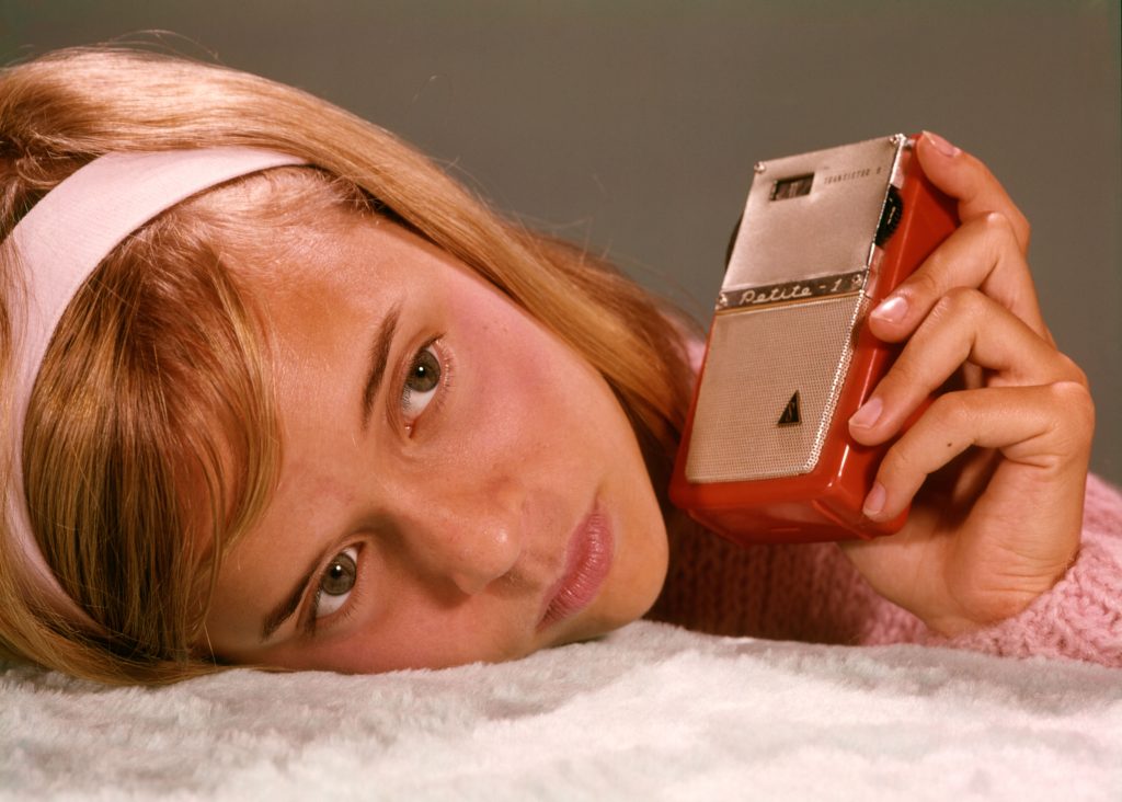 Young wistful girl listening to a vintage transistor radio