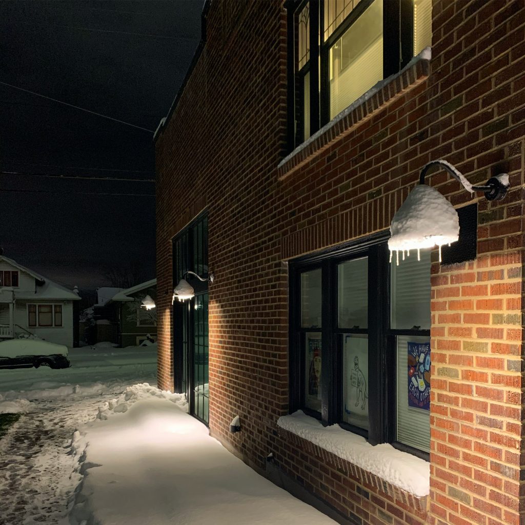 The south side of the building at at night, with glowing light and icicles hanging down.
